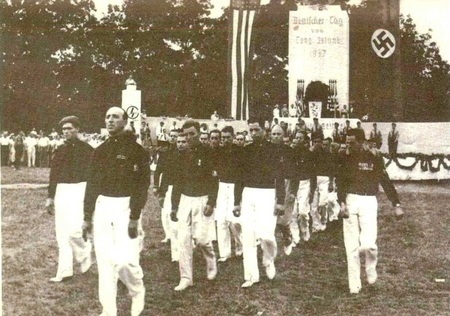 Two dozen young men marching with a American and German American Bund flag. 